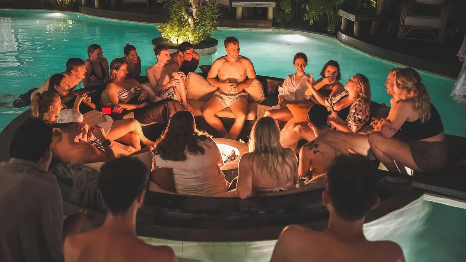 Founders around the fire pit in the pool at night