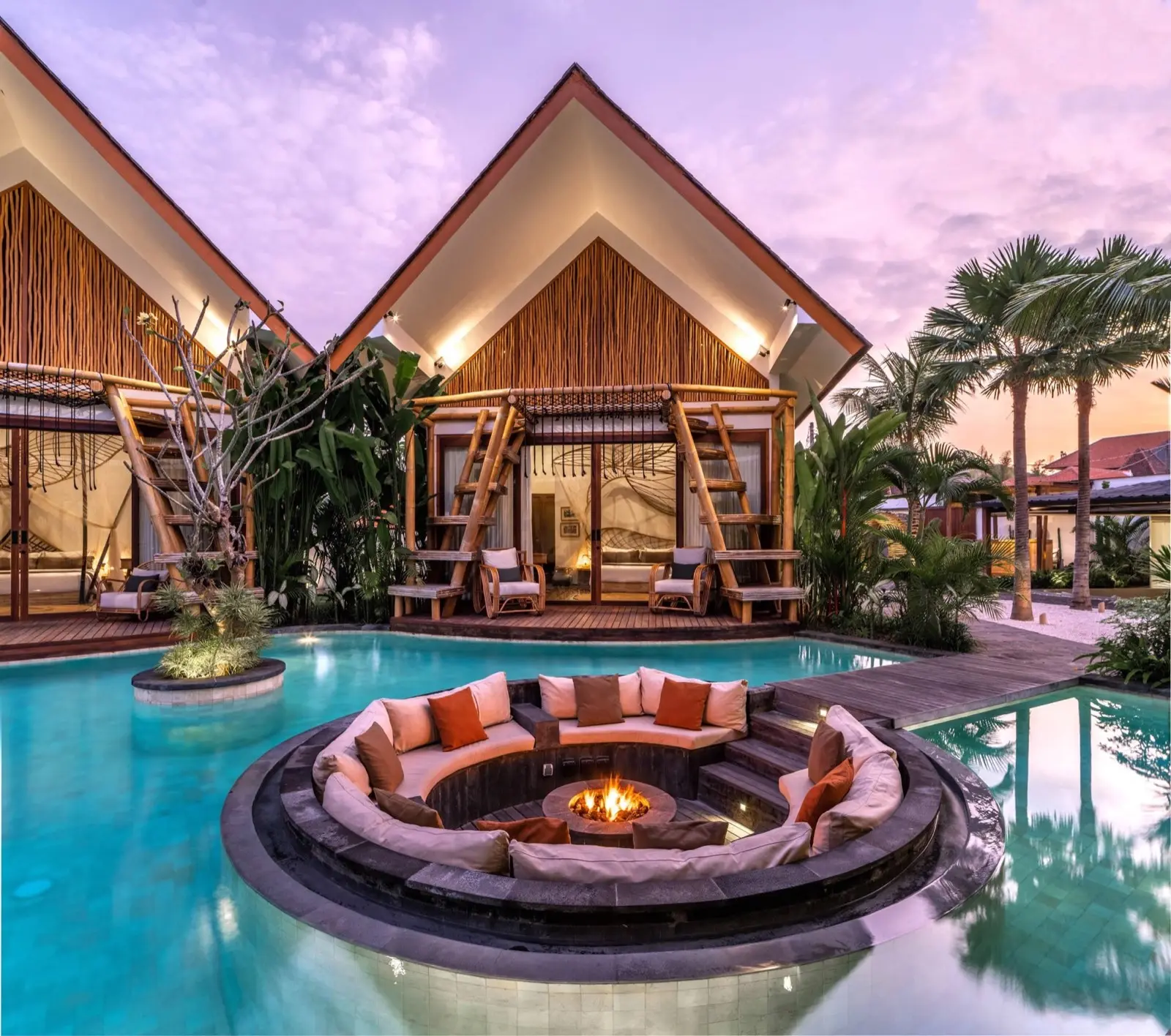 The sunken fire pit in the villa pool at dusk, timber villas behind